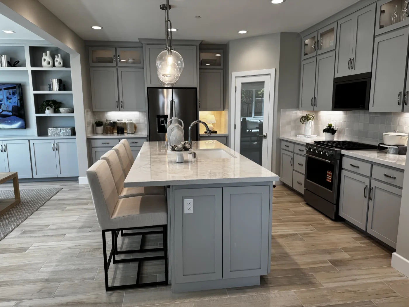 Amoruso Ranch kitchen with light gray cabinets, quartz island, and built-in display shelving